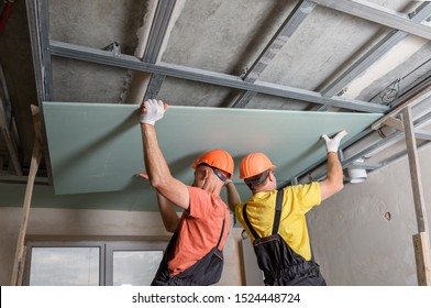 Workers Are Lifting Plasterboard For Further Attaching To The Ceiling.