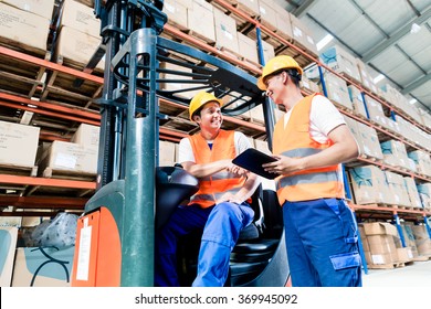 Workers In Logistics Warehouse At Forklift Checking List