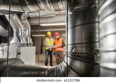 Workers making final touches to HVAC system. HVAC system stands for heating, ventilation and air conditioning technology. Team work, HVAC, indoor environmental comfort concept photo. - Shutterstock ID 611517386