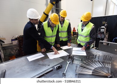 Workers And Manager In Safety Helmets Working With Documents At Factory