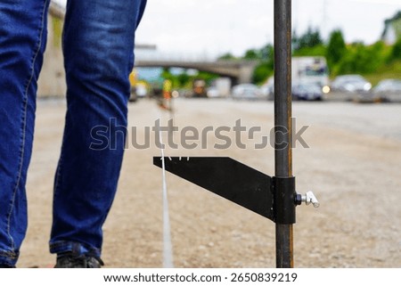 Workers measuring a straight line for the application of asphalt on a road construction site, ensuring precision in the paving process for a smooth and accurate road surface.