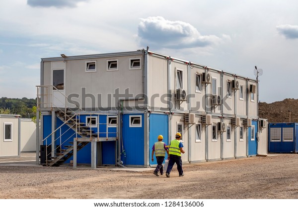 Workers at mobile\
containers and cabins base for the site manager and employees.\
Construction site work site fast build mobile prefabricated\
container houses.\
