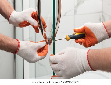 Workers are mounting door handles of the shower enclosure. - Shutterstock ID 1920352301