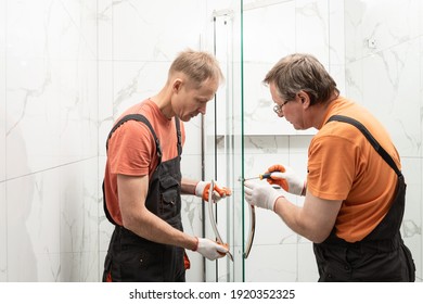 Workers are mounting door handles of the shower enclosure. - Shutterstock ID 1920352325