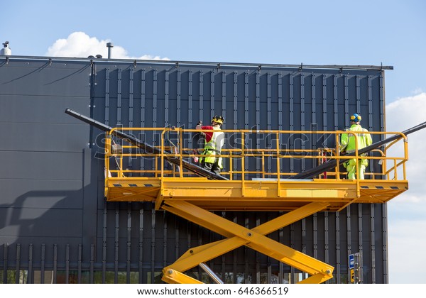 Workers on the aerial work platform at facade\
installation work