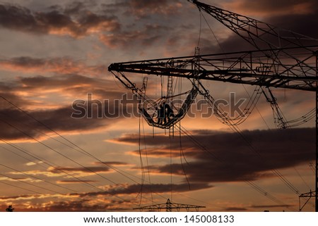 Workers on a highvoltage tower at sunset