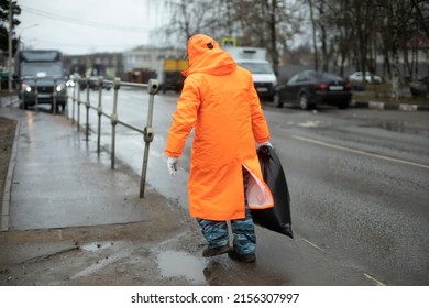 Workers On Road. Road Workers Clean Up Garbage. People In Orange Clothes. Transport Service Maintains Side Of Highway.