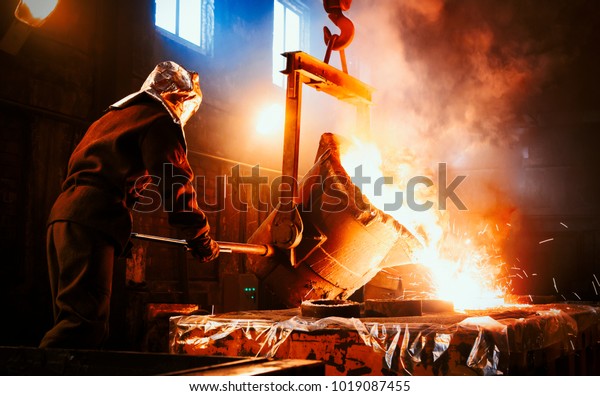 Workers operates at the metallurgical plant.\
The liquid metal is poured into molds. Worker controlling metal\
melting in furnaces.
