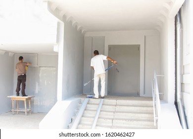 Workers Paint The Facade Of A Residential, Apartment Building. Painting Work On The Street. Back View. No Faces.