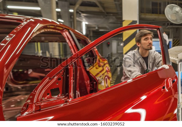 Workers paint shop car body applied decorative\
film on the door rack,\
close-up
