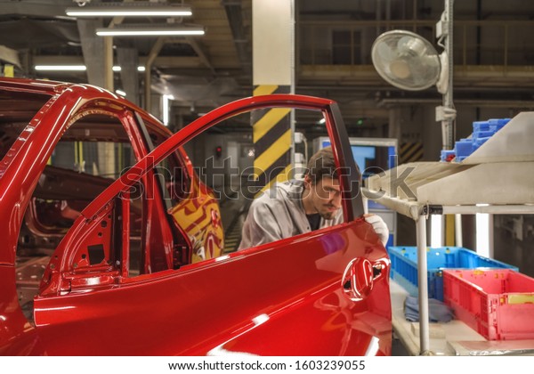 Workers paint shop car body applied decorative\
film on the door rack,\
close-up