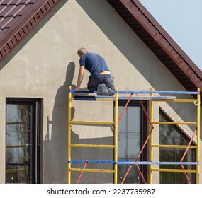 Workers are plastering the walls of the house outside.  - Shutterstock ID 2237735987