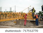 Workers in the process of removing a tower crane disassembling it bit by bit. The motor for turntable movement is being prepared for manual operation.