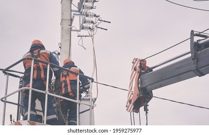 Workers in protective helmets and gear work at height using a crane, repair and maintenance of power grids,  transformer