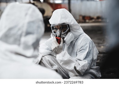 Workers in Protective Suits Checking Chemicals in Old Factory. Protecting Against Hazards and Contamination in Industrial Settings.