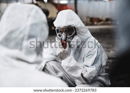 Workers in Protective Suits Checking Chemicals in Old Factory. Protecting Against Hazards and Contamination in Industrial Settings.