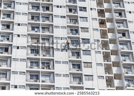 Workers are rappelling outside the building to paint it