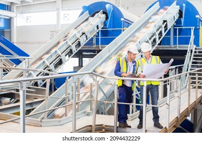 Workers Reading Blueprints In Recycling Center