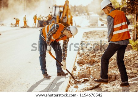 Workers in reflective vests using shovels during carriageway work
