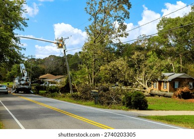 Workers remove fallen tree from house after tornado while cars pass by on t road in residential neighborhood