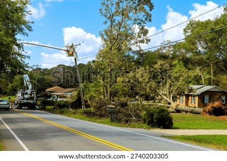 Workers remove fallen tree from house after tornado while cars pass by on t road in residential neighborhood