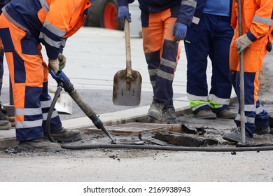 Workers Repair The Road Surface With A Jackhammer. Construction Work, Sewer Repairing And Asphalt Paving In City