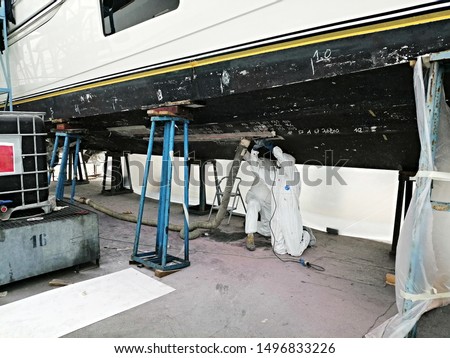 Workers sandblast, sand the yacht for painting and preparing it for launching, maintenance of expensive yachts, repairs