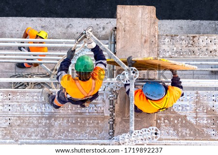 Workers seen from above setting scaffolding on a facade