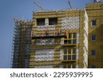 Workers sheathe the outer walls of a brick house with insulation. Insulation of the facade of the building. The concept of exterior decoration, moisture protection, sound insulation, energy saving.