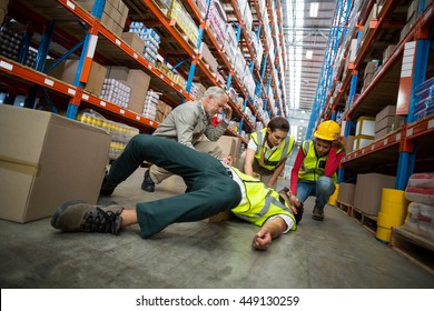 Workers taking care about their colleague lying on the floor in a warehouse