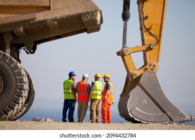 Workers Talking By Machinery In Quarry