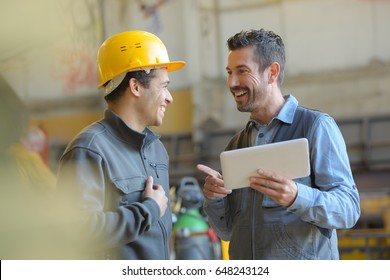 workers talking and laughing at a factory - Shutterstock ID 648243124