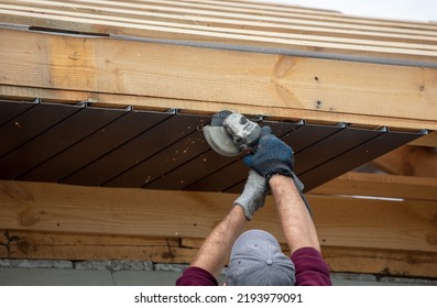 Workers Trim The Metal Roof On The Wooden Roof Of The House.