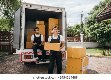 Workers unload cardboard boxes from a van. Movers work together in a relocation service. Cooperation among colleagues. Smiling employees carrying orders. relocation cooperation Moving Day