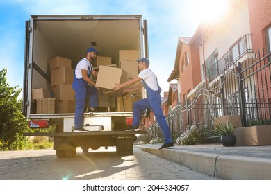 Workers unloading boxes from van outdoors. Moving service - Shutterstock ID 2044334057