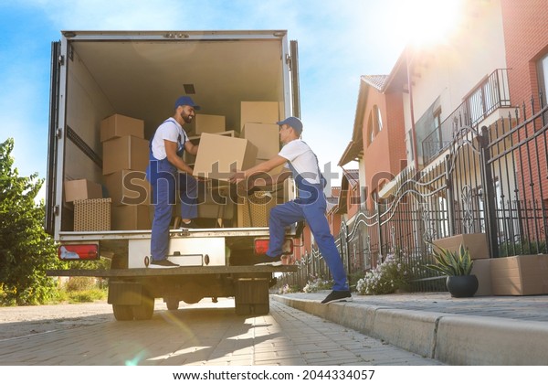 Workers\
unloading boxes from van outdoors. Moving\
service