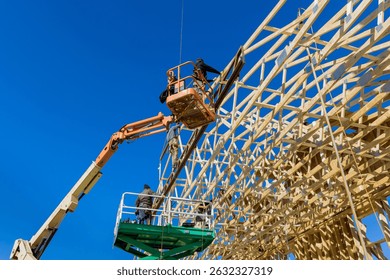 Workers use machinery to construct trusses wooden framework under bright blue sky in work area