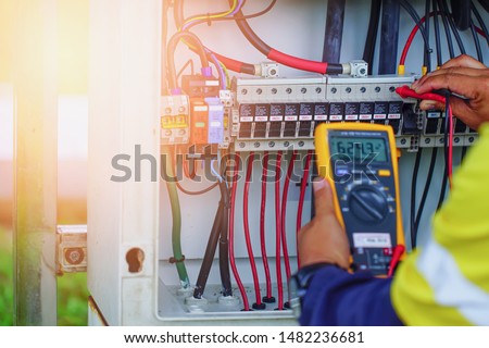 Workers use Multimeter to measure the voltage of electrical wires produced from solar energy for confirm to systems working normal.