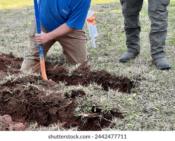 Workers using hand digging and heavy equipment to excavate a residential yard. Locating and repairing a water line.
