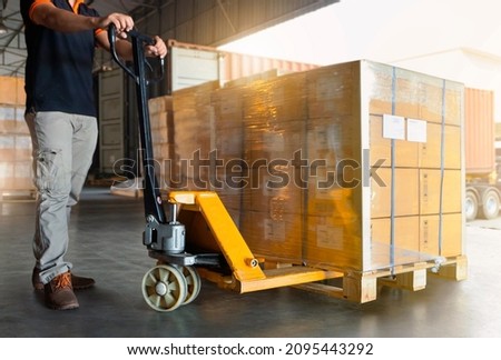 Workers Using Hand Pallet Jack Unloading Package Boxes at The Warehouse. Delivery Shipment Boxes. Trucks Loading at Dock Warehouse. Supply Chain. Warehouse Shipping Transport and Logistics.	