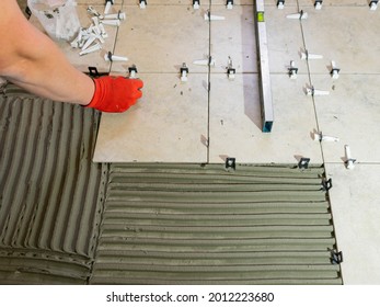 Workers are using plastic clamps and wedges to leveling the ceramic tile on the floor. Tile leveling system.