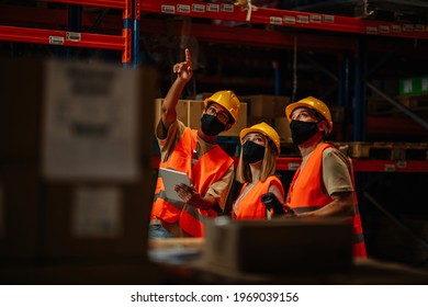 Workers Using Technology And Wear Face Mask To Prevent COVID-19 Coronavirus Infection In Distribution Center. Business Teamwork Concept.