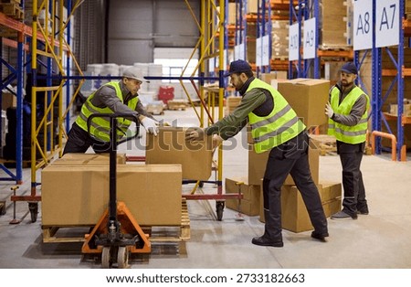 Workers in warehouse loading boxes on pallet. Loaders prepare shipment with pallet jack and stack parcels. Safety vests and logistics ensure fast order flow. Concept of teamwork and logistics.