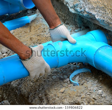Workers are water pipes with PVC joints Elbow allows the split to the left or right, which must penetrate concrete walls to make PVC pipe coming out the other side of the building. 