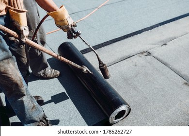 Workers Waterproofing Flat Concrete Roof Using Blowtorch And Bituminous Membrane Rolls 