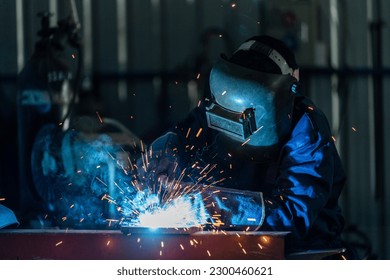 A workers wearing industrial uniforms and welded iron mask at steel welding plants, Industrial safety first concept. - Powered by Shutterstock