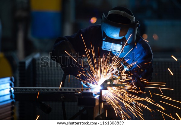 Workers wearing\
industrial uniforms and Welded Iron Mask at Steel welding plants,\
industrial safety first\
concept.