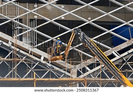 Workers welding and assembling building frame, working at height on crane lifting platform, construct new structure, construction work. Welding crew on building site