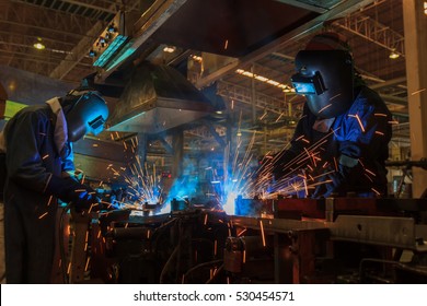 Workers Are Welding Assembly Car Parts In Automotive Industrial Factory With Protection Mask 
