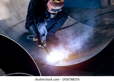 Workers are welding iron plates in a small dark workshop
